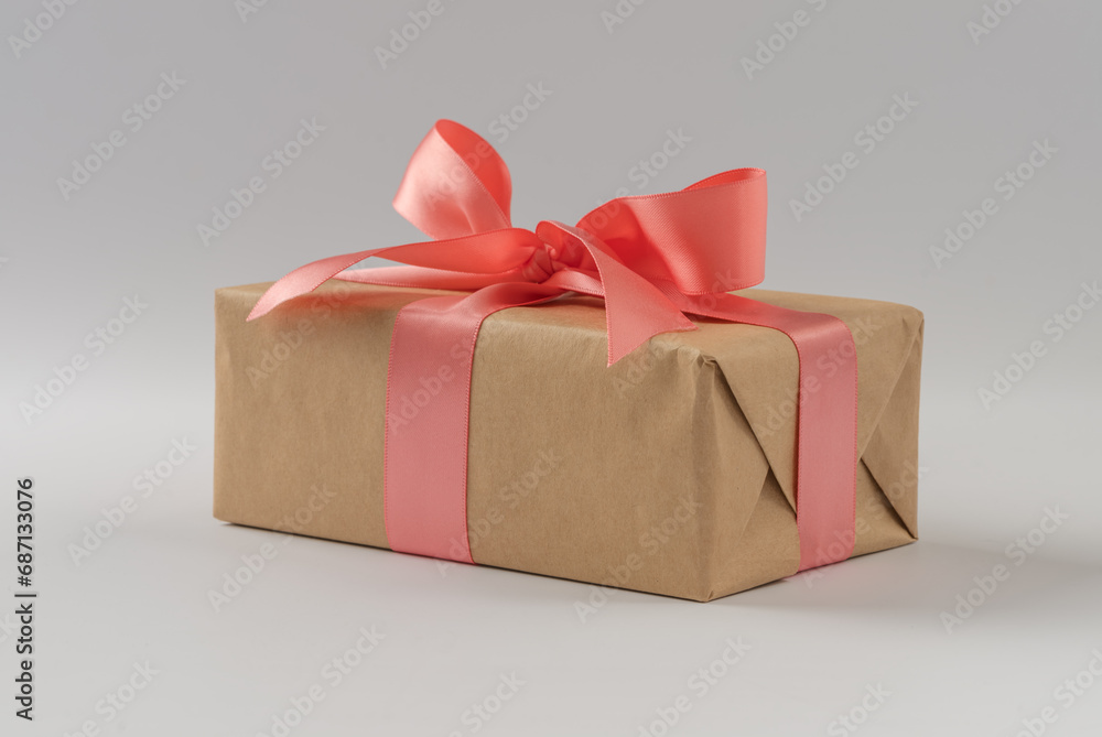 Brown paper gift box with silk rose ribbon on gray background Brown paper gift box with silk rose ribbon on gray background