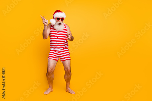 Full length photo of cheerful funny guy wear new year swimsuit hat sunglass enjoying disco empty space isolated yellow color background