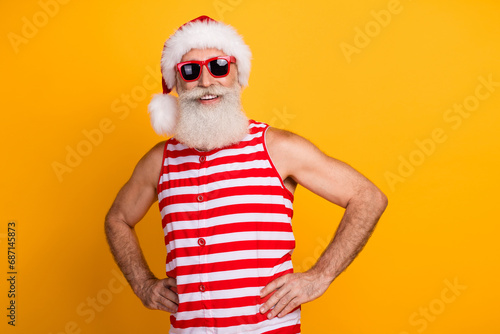 Photo of cool cheerful senior guy dressed swimwear hat glasses enjoying christmas vacation empty space isolated yellow color background