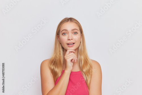 Portrait photo of cute girl with long hair posing alone on white background holding her hand at her chin, beauty concept, copy space