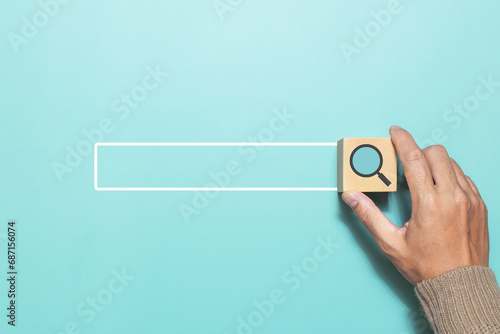 A man putting wood cube with magnifying glass icon that represents searching data information networking. Concept for network web and technology photo