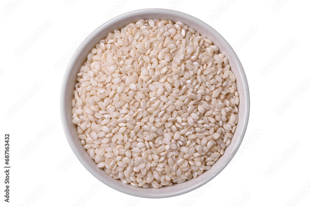 White uncooked rice in a round ceramic bowl on a dark concrete background White uncooked rice in a round ceramic bowl on a dark concrete background