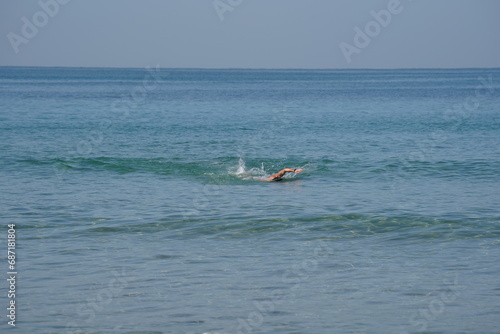 Young strong athletic man swimming in the sea under the sunshine. Sport' vacation healthy lifestyle. Mediterranean Sea in winter
