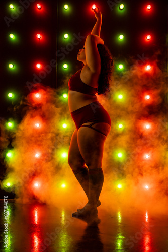 Female in sports bra and short posing in front of red and green christmas themed light wall