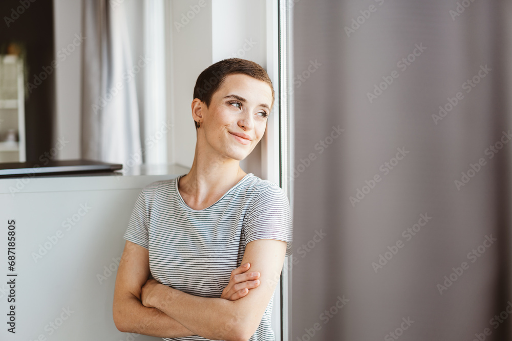Smiling Young Woman Leaning on Wall and Looking Out Office Window Smiling Young Woman Leaning on Wall and Looking Out Office Window