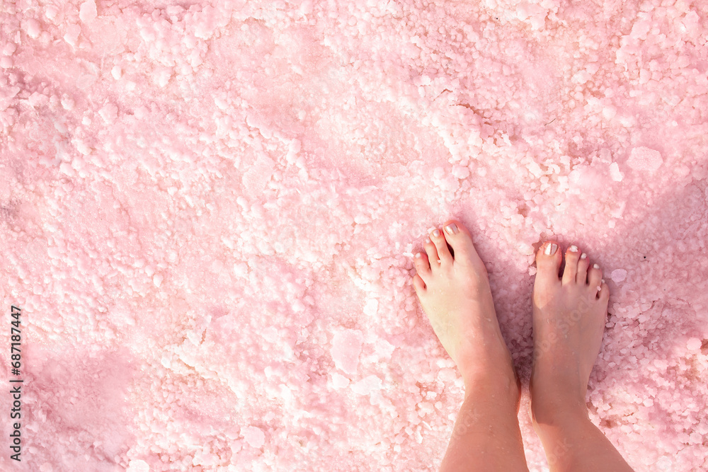 Fototapeta premium Pink lake. Girl's feet on water with pink salt. A unique rare natural phenomenon. Salt Lake.