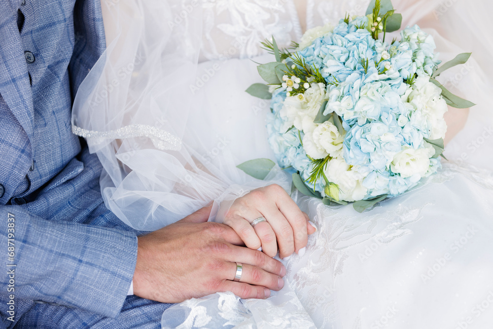 Newlyweds' hands with wedding rings and wedding bouquet Newlyweds' hands with wedding rings and wedding bouquet