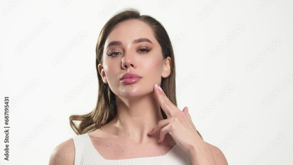 Portrait of an attractive dreamy tender girl doing a face and neck massage, isolated on a light background. Self care concept. Advertising of cosmetology and cleanliness. Portrait of an attractive dreamy tender girl doing a face and neck massage, isolated on a light background. Self care concept. Advertising of cosmetology and cleanliness.