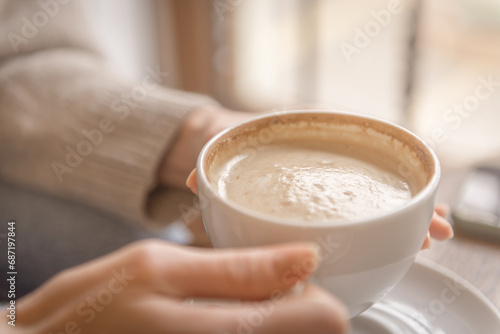 Cup of coffee in the hands of a young woman
