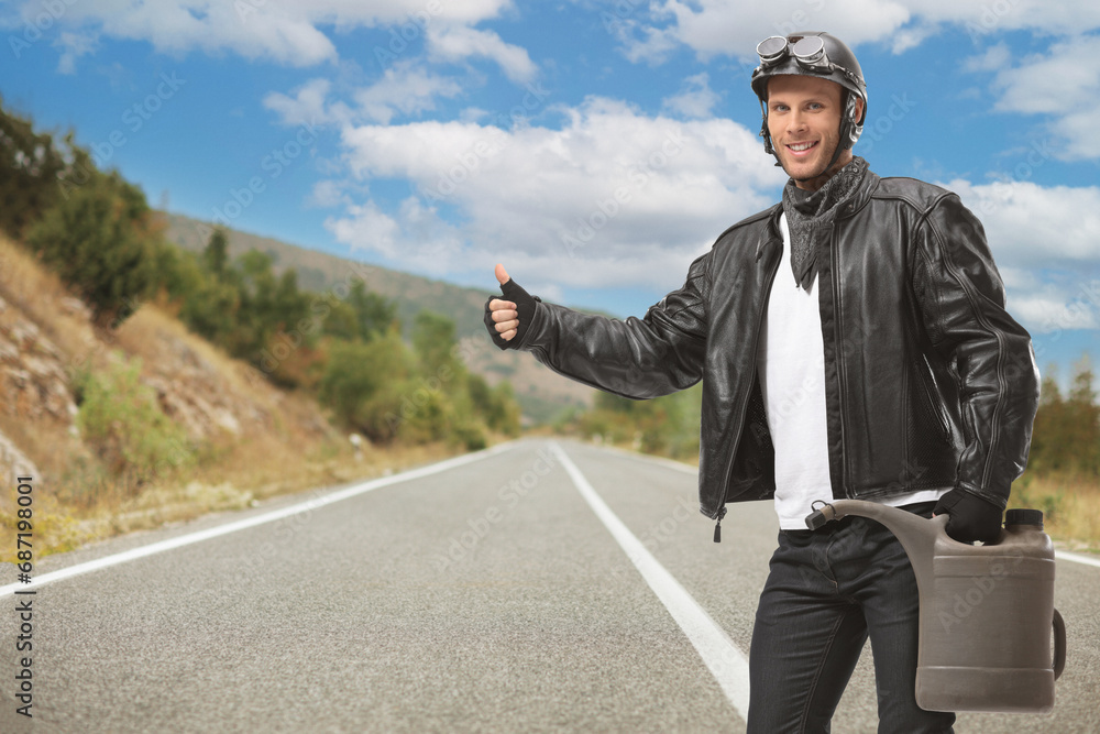 Young biker holding a gas container and hitchhiking Young biker holding a gas container and hitchhiking