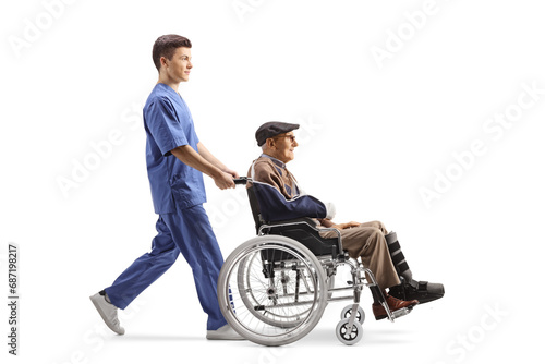 Male health care worker pushing an elderly injured man in a wheelchair