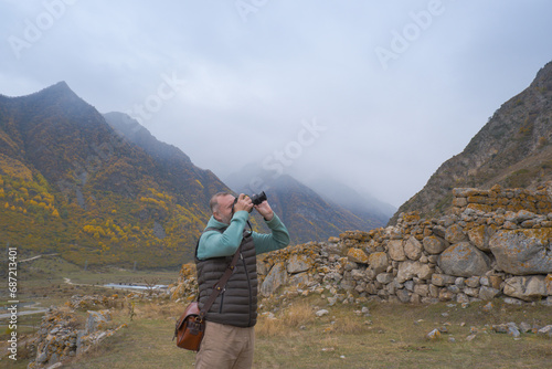 A male tourist takes pictures of a beautiful autumn mountain foggy landscape using a camera.