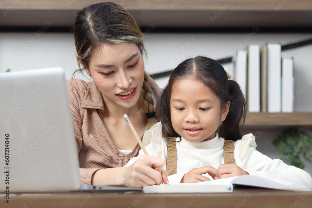 Asian little cute girl learning and studying her lesson with mother at home, schoolgirl pupil does homework with female tutor teacher, happy child student learning writing, homeschool kid education. Asian little cute girl learning and studying her lesson with mother at home, schoolgirl pupil does homework with female tutor teacher, happy child student learning writing, homeschool kid education.