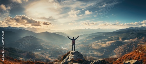 Young man standing on a to celebrates reaching the top of the mountain photo