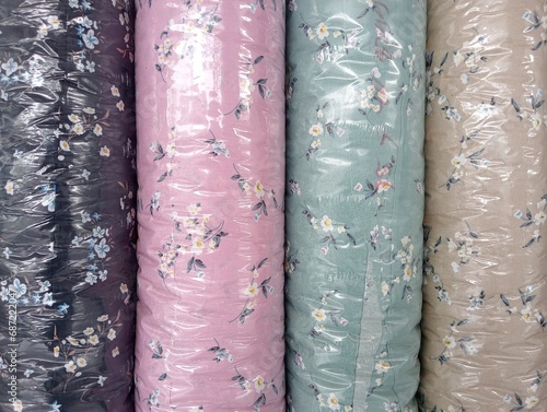 Colorful material fabric rolls texture samples. Fabric rolls of colorful flowers material. Carton reels with colorful textile on a retail market stall.