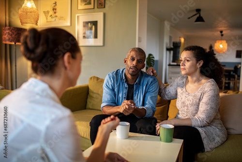 Couple in conversation with woman therapist, serious discussion at home photo