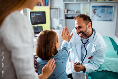 Smiling doctor high fiving little girl at the hospital photo