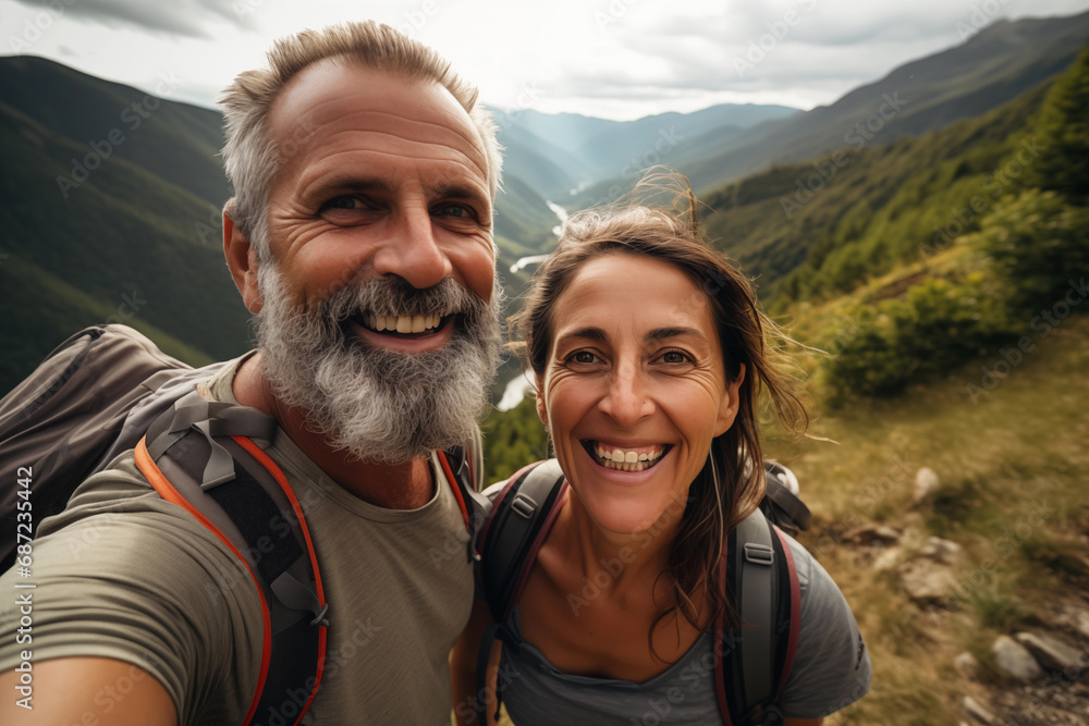 Portrait of a happy senior couple hiking in the mountains. They are looking at camera and smiling.