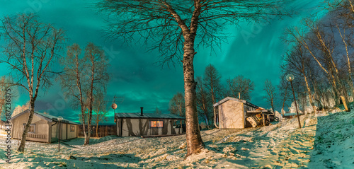 Beautiful Northern lights panorama above small wooden mountains cottage in Northern Sweden  Lapland  Joesjo. Green light of Aurora Borealis  winter time