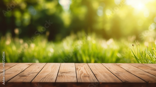 Beautiful blurred natural background with floor of dark brown wooden planks and young green juicy grass in sun with bokeh effect. Copy space.