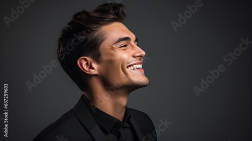 Portrait of fashionable male model, shot from the side, smiling and looking towards nose, grey background