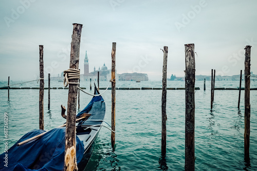 A serene lake landscape is interrupted by the wooden gondola tied to the pier, creating a sense of both freedom and restraint in the vast expanse of sky and water © Armen