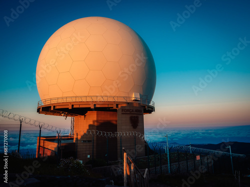 An ethereal sunset ignites the sky above a grand observatory in madeira, where a colossal white sphere rests atop the building, beckoning travelers to peer through its telescopic lens and explore the