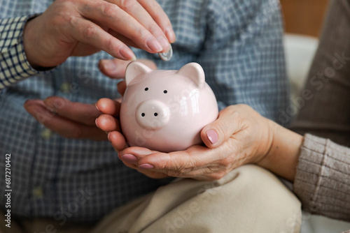 Saving money investment for future. Senior adult mature couple hands putting money coin in piggy bank. Old man woman counting saving money planning retirement budget. Saving investment banking concept