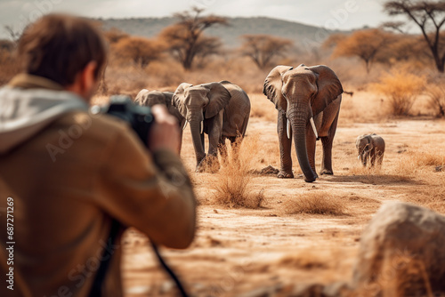 Man traveler taking photo of elephants at African savannah. Professional wildlife photographer photo