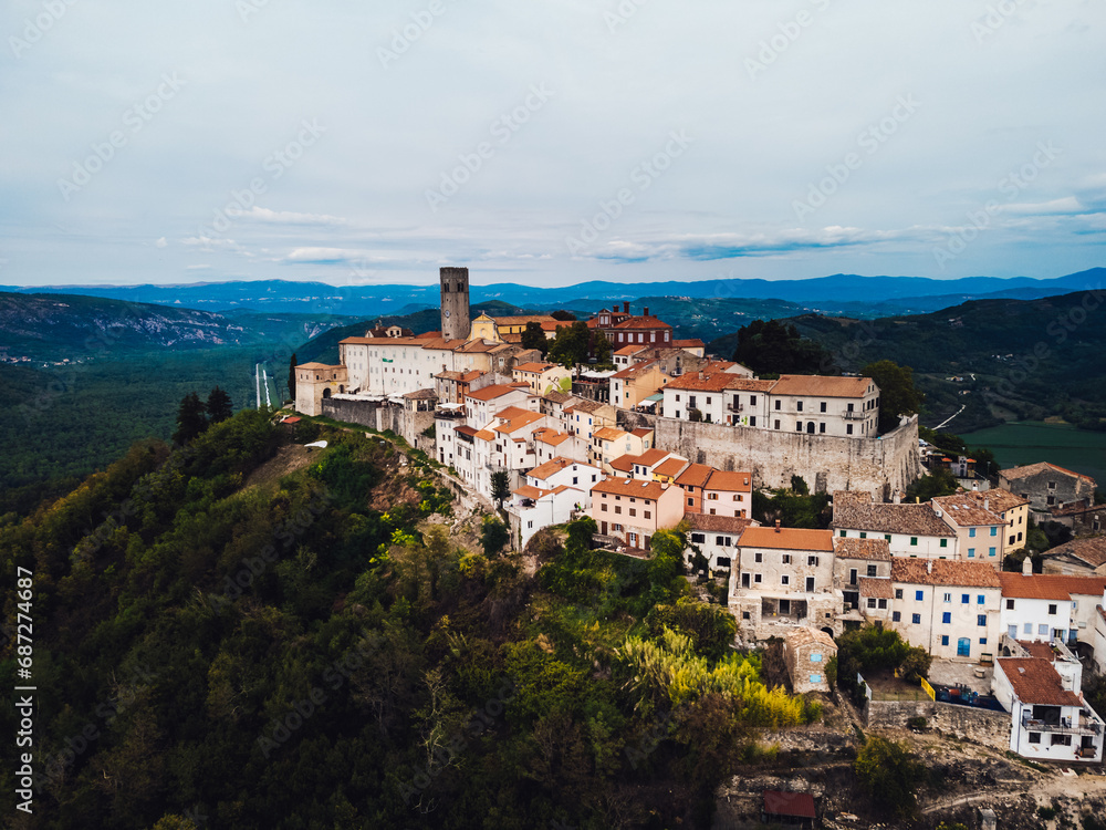 Amidst the vastness of nature's canvas, a city on a hill stands tall, its buildings and castles blending into the landscape as the summer sky paints a breathtaking panorama above