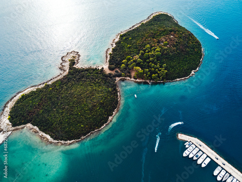 Amidst the vast expanse of crystal blue waters, an island stands resilient and proud, its rugged coast dotted with lush greenery, a wild oasis in the midst of a serene ocean photo