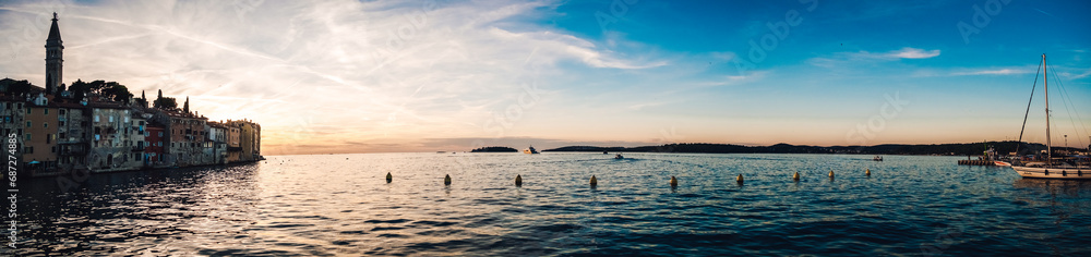 Fototapeta premium A breathtaking sunset over the tranquil lake, as boats gracefully glide through the glistening water, mirroring the vibrant sky above