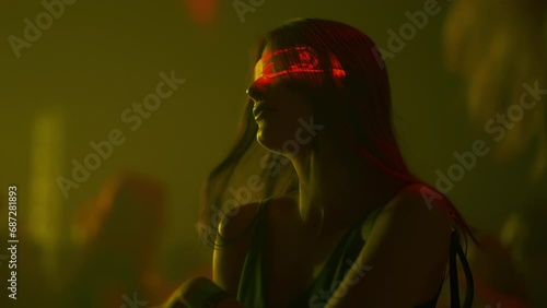 Woman dancing at crowded dance floor in colorful illuminated nightclub disco party. Futuristic style sensual clubber girl in neon glow glasses. Fashion female in club, cyberpunk atmosphere techno rave