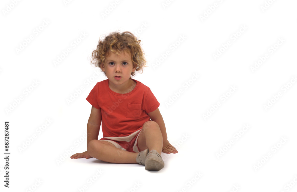 front view of a boy dressed in summer clothes sitting on group and looking at camera on white background (3 year old) front view of a boy dressed in summer clothes sitting on group and looking at camera on white background (3 year old)