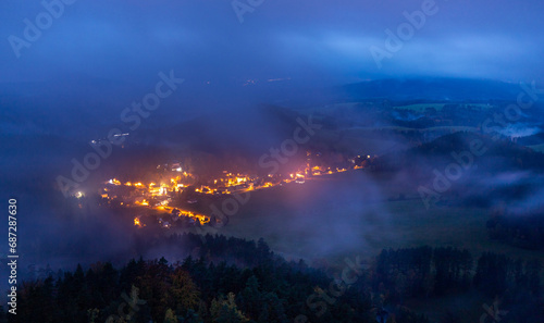 fog over village and meadows in mountain valley