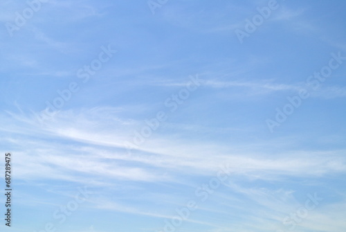 Clear blue sky with white cirrus clouds, small and large wispy, feathery, fluffy clouds alternating and moving slowly, nature background 
