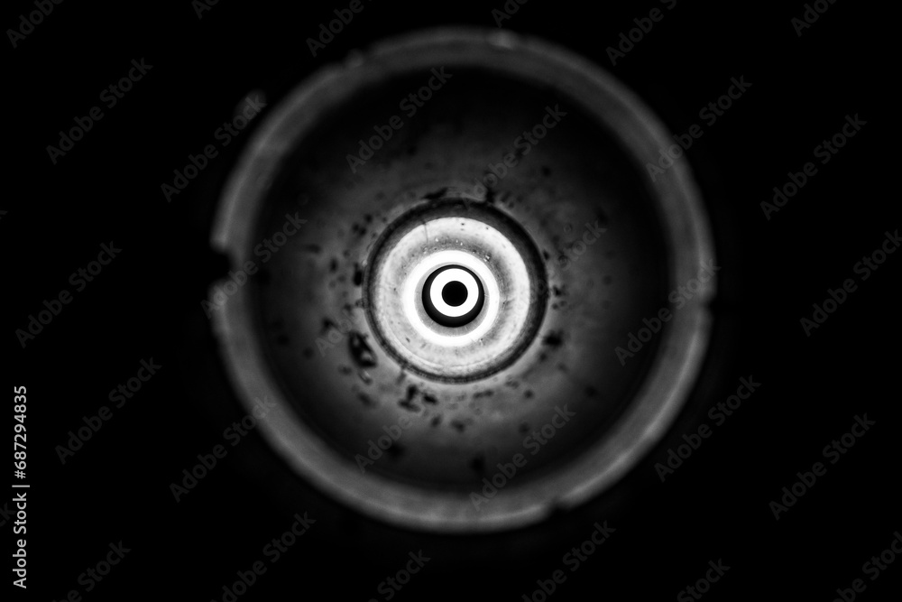 Flashlight light in an empty used anti-tank grenade launcher as a background, bright light in a circle, light , black and white photo Flashlight light in an empty used anti-tank grenade launcher as a background, bright light in a circle, light , black and white photo