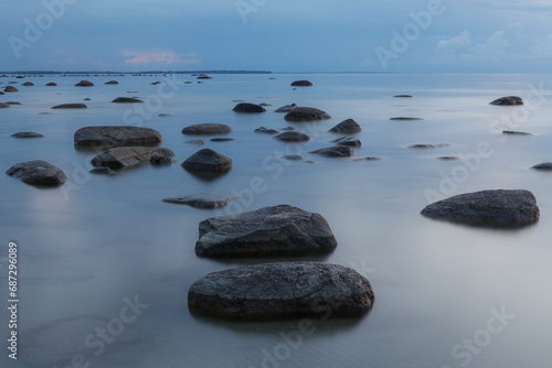 Blue hour after sunset. Smooth water and erratic boulders. Calm sea water. Long exposure