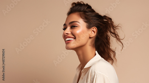 Portrait of young european fashionable female model, shot from the side, smiling, looking to the side, beige, background
