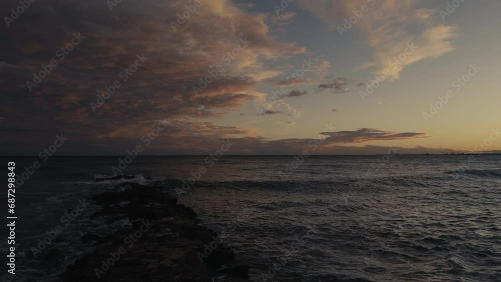 Storm at sea in winter in Benicassim. Waves crash against the rocks on a winter evening. On the horizon there is a city against the backdrop of mountains. Spain. Province of Castellon Storm at sea in winter in Benicassim. Waves crash against the rocks on a winter evening. On the horizon there is a city against the backdrop of mountains. Spain. Province of Castellon
