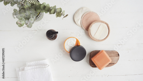 Zero waste organic cosmetics concept flat lay composition with reusable make-up remover discs, organic soap, cream, glass bottle, white towel and dried eucalyptus leaves. photo