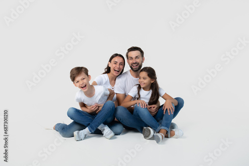 Happy excited beautiful and smiling dad, mommy and them kids sitting on the floor isolated on white background