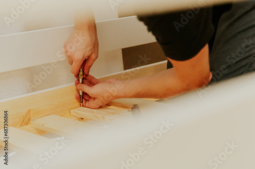 A young man installs a bunch of frame boards on a bunk bed.