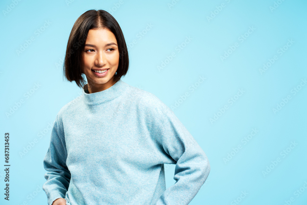 Positive cheerful Asian woman wearing casual clothes looking away posing isolated on blue background Positive cheerful Asian woman wearing casual clothes looking away posing isolated on blue background