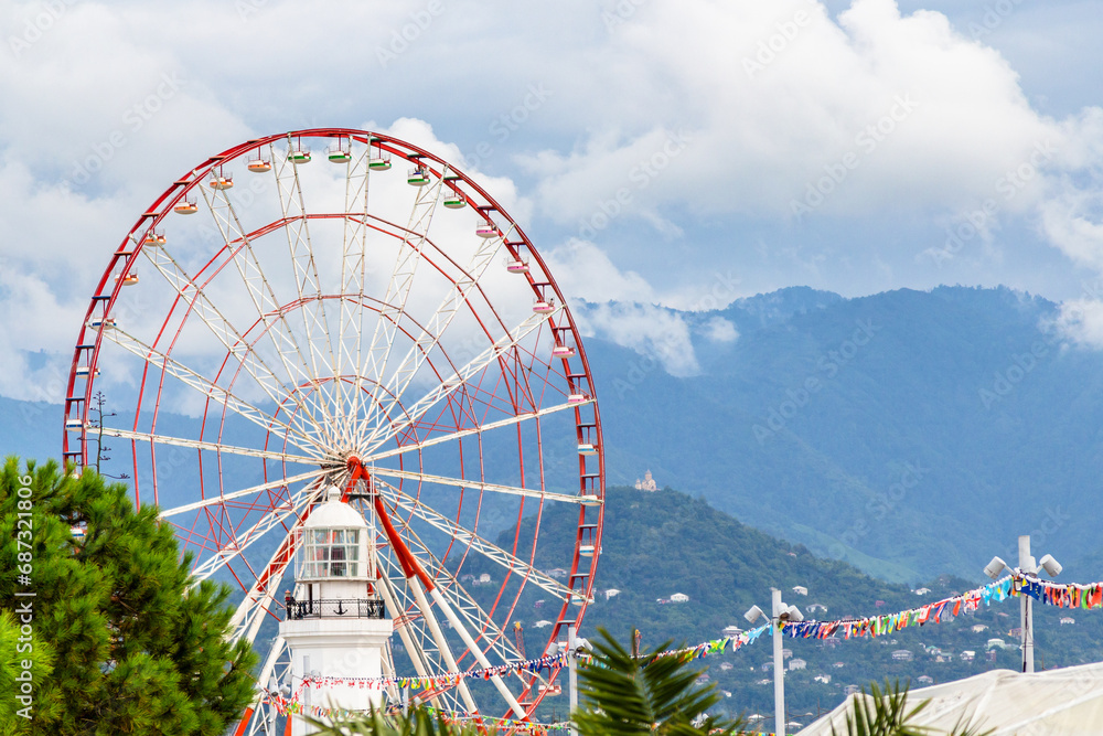 travel to Georgia - view of Ferris wheel, old lighthouse and mountains with rain clouds in background in Batumi city on cloudy autumn day
