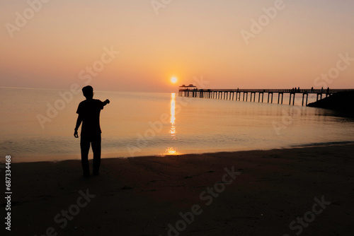 silhouette of a man walking on the beach at sunset