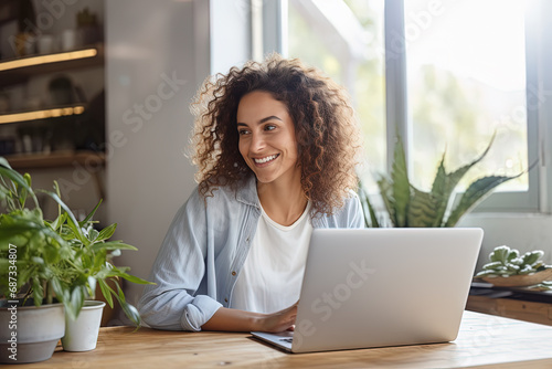 mujer de negocios teletrabajando desde su casa frente al ordenador, en una habitación rodeada de plantas, elementos naturales y luz natural photo