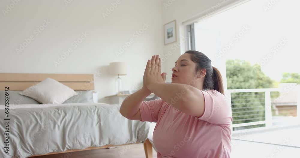 Plus size biracial woman sitting on floor practicing yoga meditation, copy space, slow motion Plus size biracial woman sitting on floor practicing yoga meditation, copy space, slow motion