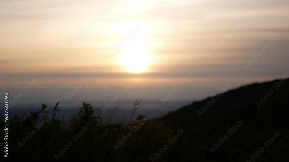 Video filming at dusk from wild grasses and hills. The sun sets behind the horizon through dense layers of clouds, it is barely visible. Video filming at dusk from wild grasses and hills. The sun sets behind the horizon through dense layers of clouds, it is barely visible.