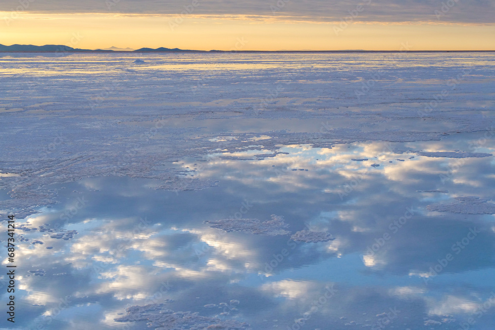 Reflections of white clouds and the blue sky on the surface of the Uyuni Salt Flat Lake, Bolivia, a popular travel destination